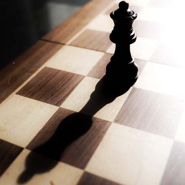 Queen chess piece casting long shadow.