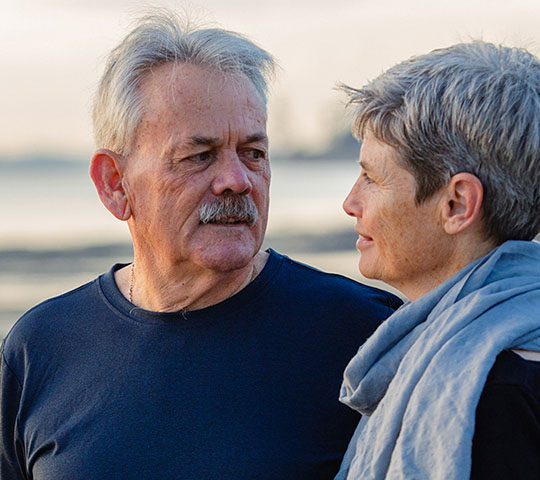 An older man and woman on a beach.