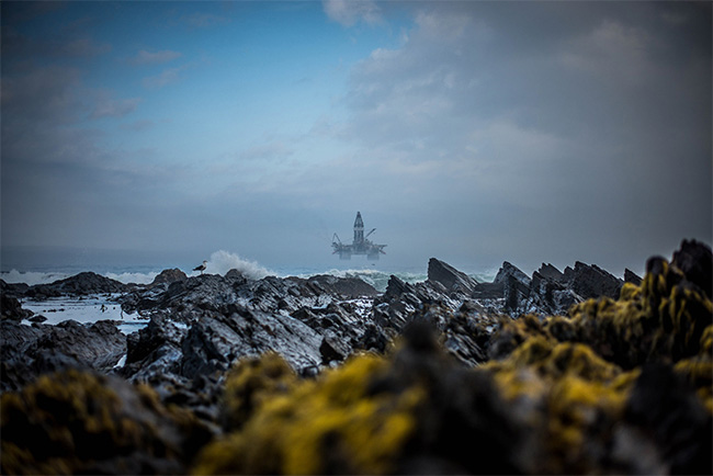 An isolated oil rig at sea off a rocky coastline