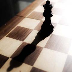 Queen chess piece casting long shadow.