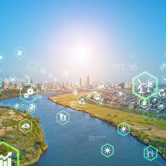 sustainability icons imposed over photo of a green city with winding river